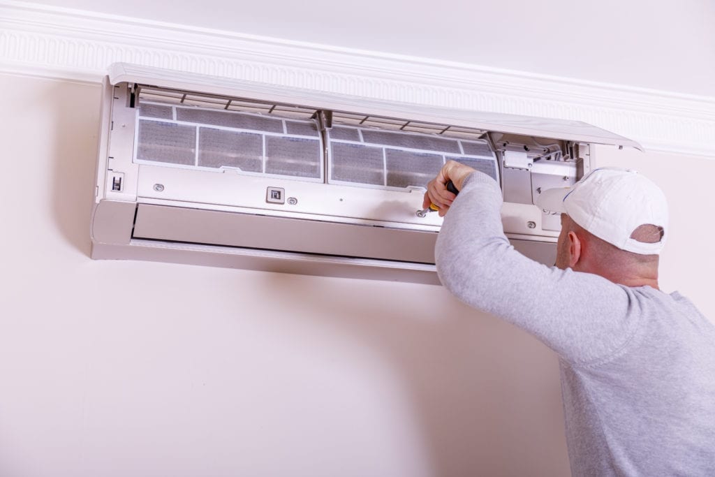 Repairman in uniform installing the outside unit of air conditioner